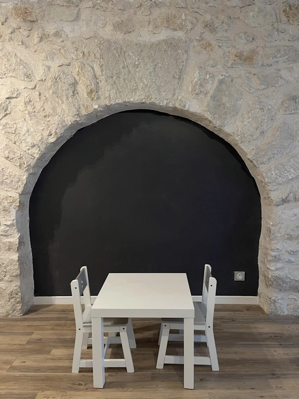 Coin enfant du cabinet : petite table et tableau noir dans le mur en pierre